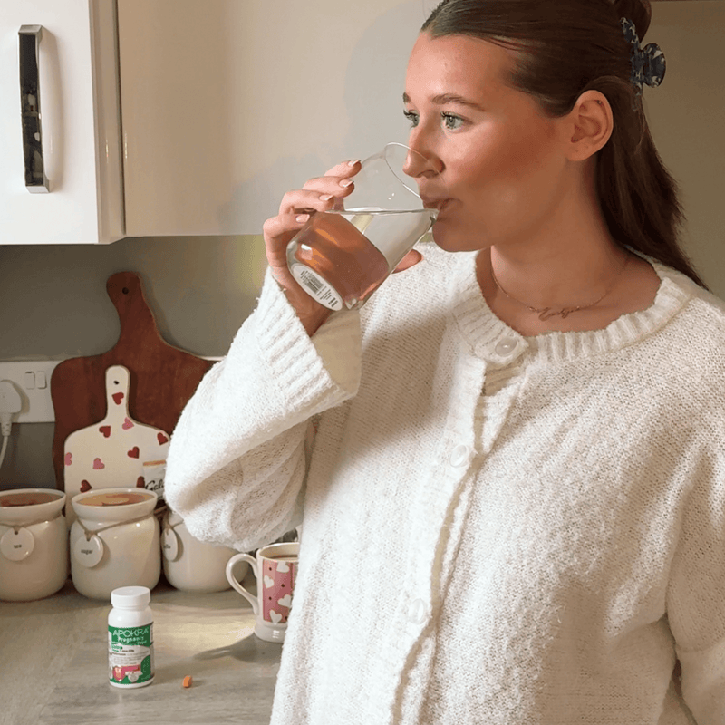 Woman drinking from a glass in a kitchen setting