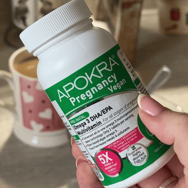 Hand holding the APOKRA Pregnancy vegan multivitamin bottle